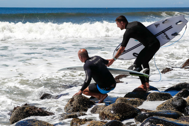 Assisted by Michael Crisp, Formston becomes half-man, half-crab to navigate the boulders edging the challenging Lennox Point surf break.