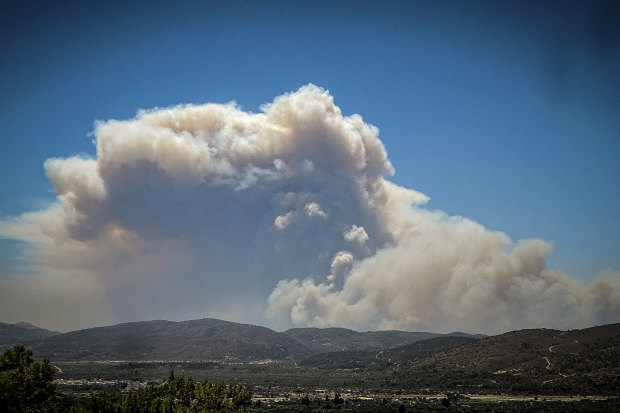 A cloud of smoke from a forest fire rises over the island of Rhodes, Greece.