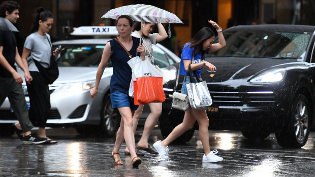 Pedestrians are seen in the CBD during a thunderstorm in Sydney.