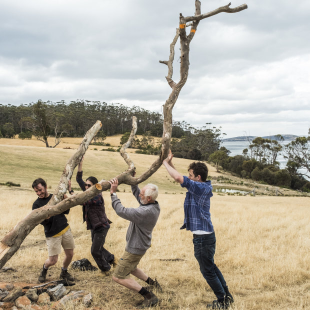 Kevin Perkins (second from right) and helpers affix an old tree to a stump, which will serve as the setting for 12 whittled bird sculptures. 