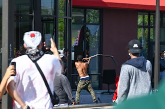 A man breaks a window at the Furniture Barn store on University Avenue West, Thursday, May 28, 2020, in St. Paul, Minnesota