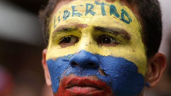 An opponent to President Nicolas Maduro, his face the colours of the Venezuelan national flag and the word for "Freedom" written on his forehead, takes part in a march in Caracas on Saturday.