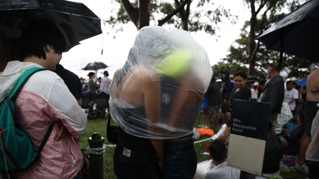 Revellers at Ms Macquarie’s Chair try and find shelter from the rain.