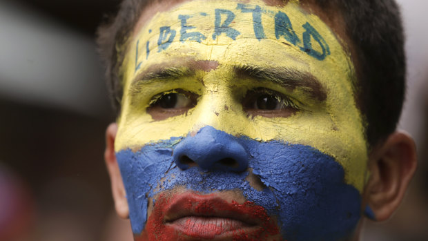 An opponent to President Nicolas Maduro, his face the colours of the Venezuelan national flag and the word for "Freedom" written on his forehead, takes part in a march in Caracas on Saturday.