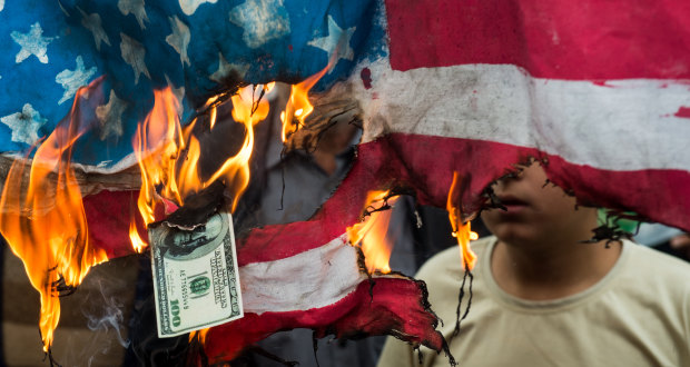 Protesters burn an American flag and a US $100 dollar bill in Tehran on Sunday.