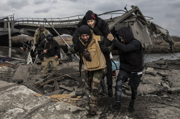 Ukrainian forces carry an elderly man as thousands flee Irpin on Monday.