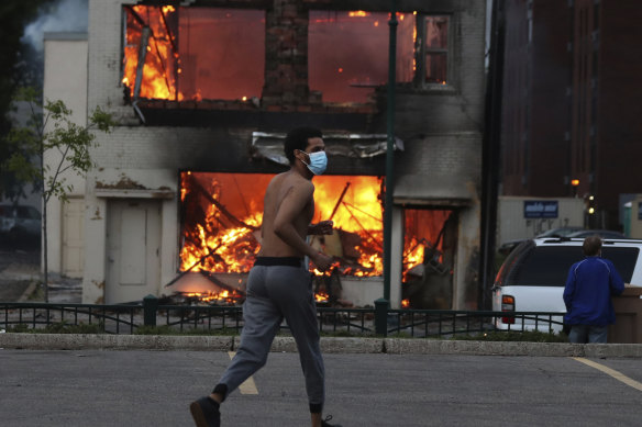 A man runs near a burning building after a night of unrest in downtown Minneapolis.