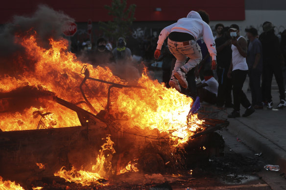 A man jumps off a burning car in a Target car park in Minneapolis.