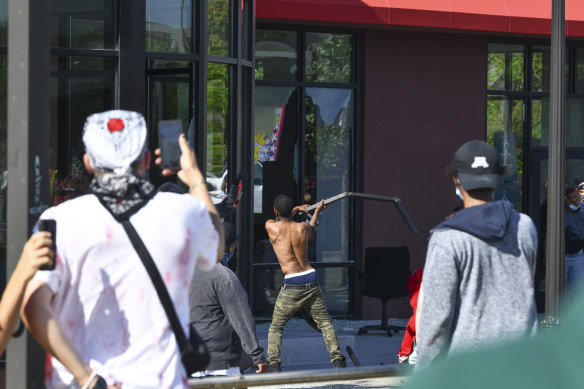 A man breaks a window at the Furniture Barn store on University Avenue West, on Thursday in St Paul, Minnesota.