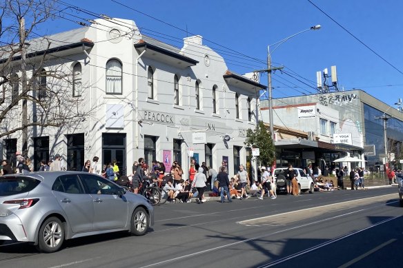 People congregate outside the Peacock Inn, on High Street in Northcote, on Sunday.