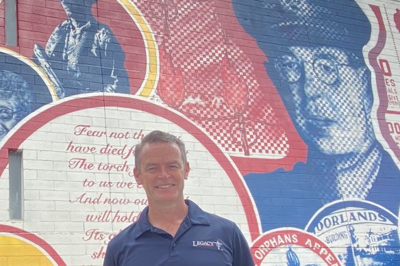 Legacy Queensland chief executive Brendan Cox in front of a mural of Legacy founder Stan Savage, an army officer from WWI and WWII.