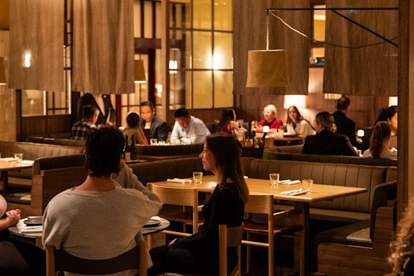 The fit-out is all dark timber panelling, marble-topped tables, vertical tiled surfaced, and burgundy and cream tones. 
