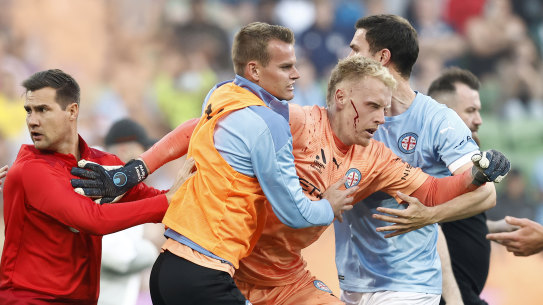 A bleeding Tom Glover of Melbourne City being escorted from the pitch on December 17, 2022.