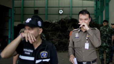 Thai police officers hold their noses to avoid inhaling a strong odor generated in Camellia Corporation, an e-waste processing factory in Bangkok.