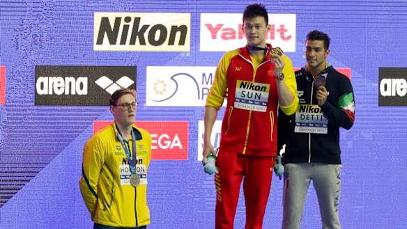 China's Sun Yang, centre, with his gold medal as silver medallist Australia's Mack Horton, left, stands away from the podium.