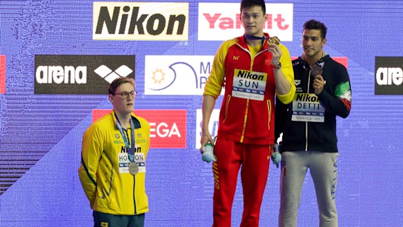 China's Sun Yang, centre, with his gold medal as silver medallist Australia's Mack Horton, left, stands away from the podium.