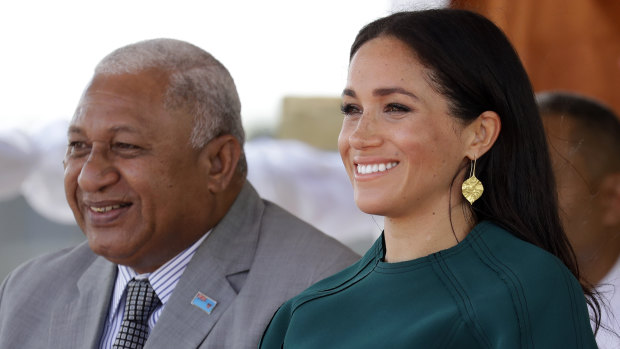 Meghan, Duchess of Sussex, smiles as she sits with Fiji's Prime Minister Frank Bainimarama.