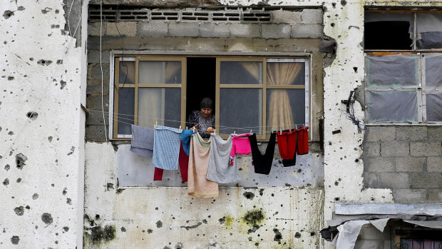 A Palestinian woman hangs clothes in a damaged apartment block, which was partially destroyed during the 2014 war between Israel and Hamas, in Beit Lahiya, Gaza Strip.