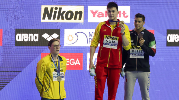 China's Sun Yang, centre, with his gold medal as silver medallist Australia's Mack Horton, left, stands away from the podium.