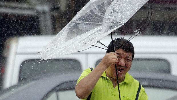A Taiwanese man holds an umbrella against powerful gusts of wind generated by typhoon Lekima in Taipei, Taiwan.