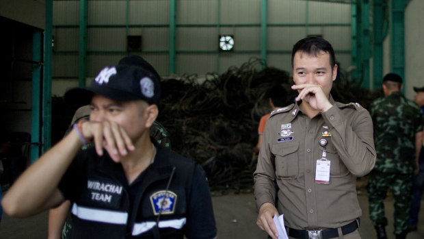 Thai police officers hold their noses to avoid inhaling a strong odor generated in Camellia Corporation, an e-waste processing factory in Bangkok.