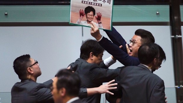 A pro-democracy politician is taken away as Hong Kong Chief Executive Carrie Lam arrives at the Legislative Council on Thursday.