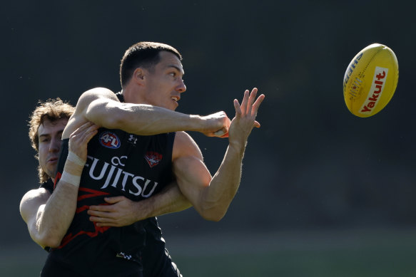 Dylan Shiel with a show of strength against Essendon vice captain Andy McGrath at training.