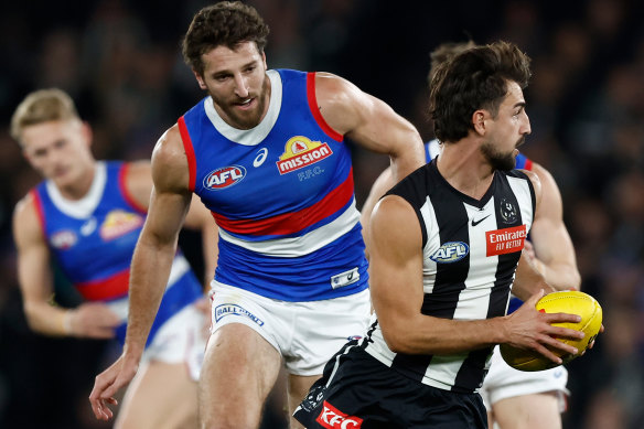 Josh Daicos of the Magpies is chased by Marcus Bontempelli of the Bulldogs.