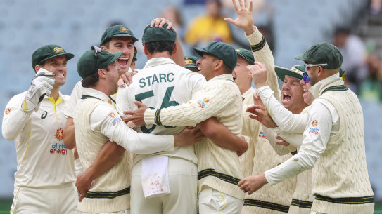Mitchell Starc embraced by his teammates after dismissing Sarel Erwee.