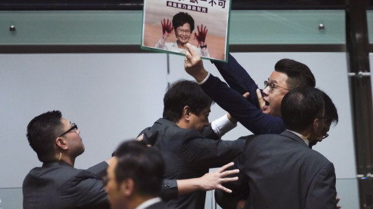 A pro-democracy politician is taken away as he shouts a slogan while Hong Kong Chief Executive Carrie Lam arrives at chamber of the Legislative Council on Thursday.