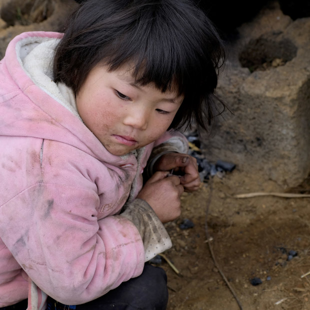 Xia Zhongmei sits at an outdoor furnace in Shanqiao, a village in China's Yunnan province.