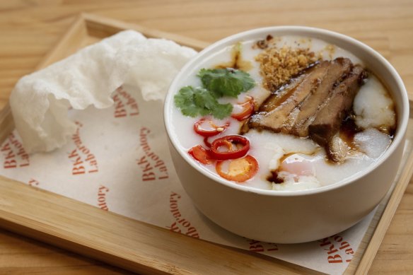 Congee with crispy pork and puffed rice paper on the side.