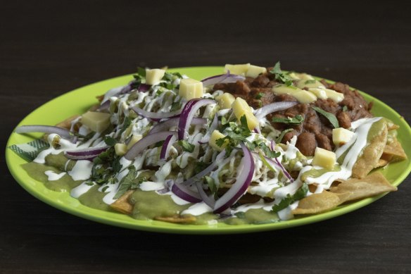 Chilaquiles, a dish of fried tortillas layered with chicken, salsa, crema and coriander, and served here with refried beans.