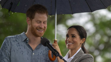 Dream team: Meghan shelters Prince Harry while he speaks at a community picnic.