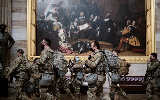 Members of the National Guard walk in the Capitol as the House of Representatives prepared to vote on impeaching President Donald Trump on Wednesday.