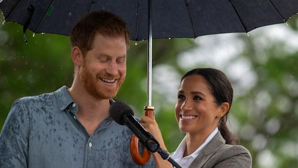 Dream team: Meghan shelters Prince Harry while he speaks at a community picnic.