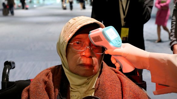 A health official scans the body temperature of a passenger at Jakarta's Soekarno-Hatta International Airport.