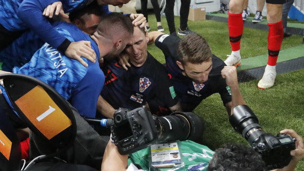 Croatia's Mario Mandzukic, centre, sits on the ground after he fell over photographer Yuri Cortez, who is in the foreground still taking photos.