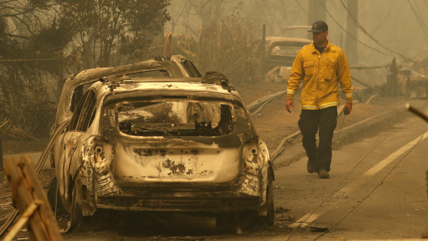 A Sonoma Valley firefighter inspects burned out cars to make sure they are clear of human remains in Paradise, California.