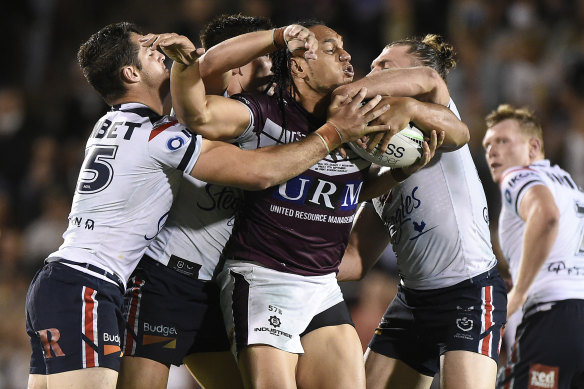 Manly prop Martin Taupau, playing his 200th NRL game, attracts the attention of three defenders on Friday night.