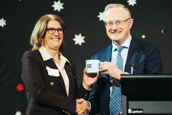 Reserve Bank governor Philip Lowe hands his successor, Michele Bullock, his optimistic coffee mug.
