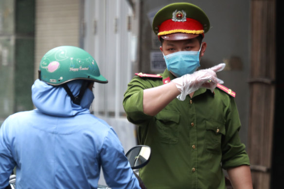 A police officer talks to a woman at the barricaded entrance of an alley where one of its residents is suspected to have COVID-19 in Hanoi, Vietnam.