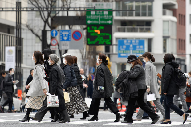Pedestrians wearing protective masks cross a road in the Ginza area in Tokyo, Japan, on Saturday, Feb. 15, 2020. Japan's economy likely suffered its biggest contraction since 2014 at the end of last year leaving it in a vulnerable state, as fallout from China's viral outbreak threatens to turn a one-quarter-slump into a recession.