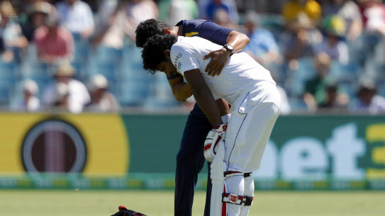 Blow: Sri Lankan batsman Kusal Perera is helped from the ground by a trainer after being struck on the helmet.