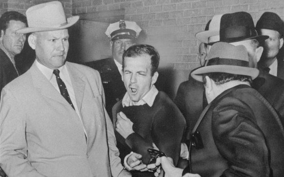 Detective Jim Leavelle (left) escorts Lee Harvey Oswald as Dallas nightclub owner Jack Ruby, foreground, shoots Oswald from point-blank range in a corridor of Dallas police headquarters, 1963. 