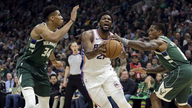 The 76ers' Joel Embiid drives between Bucks duo Giannis Antetokounmpo and Eric Bledsoe.