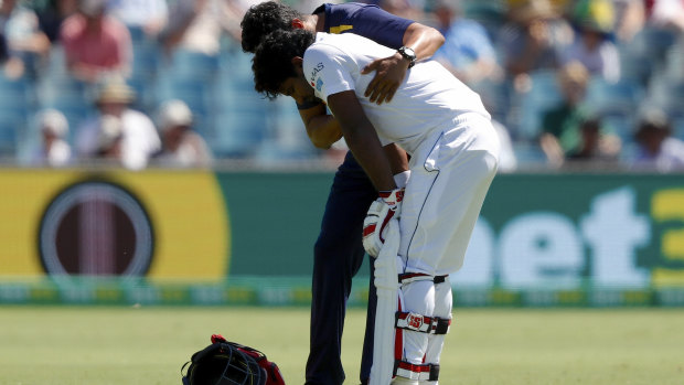 Blow: Sri Lankan batsman Kusal Perera is helped from the ground by a trainer after being struck on the helmet.