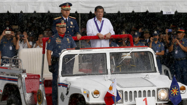 President Rodrigo Duterte, right, reviews a police  gathering under a sudden downpour last week.