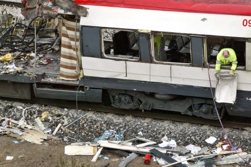 A Spanish railway worker cleans up debris out of a destroyed train in Madrid in March 2004.