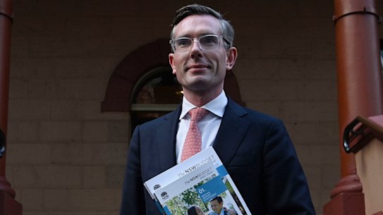 NSW Treasurer Dominic Perrottet holding the budget in front of Parliament House.